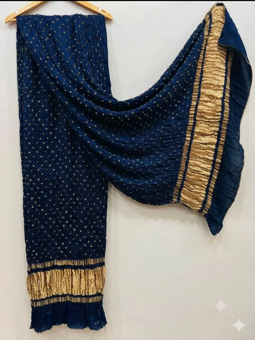 Navy blue crinkled dupatta with gold dotted embellishments and broad gold border draped on a hanger