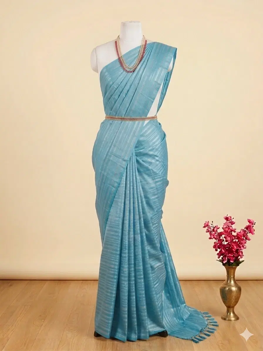 Light blue textured saree draped on mannequin with layered necklace and tassel pallu