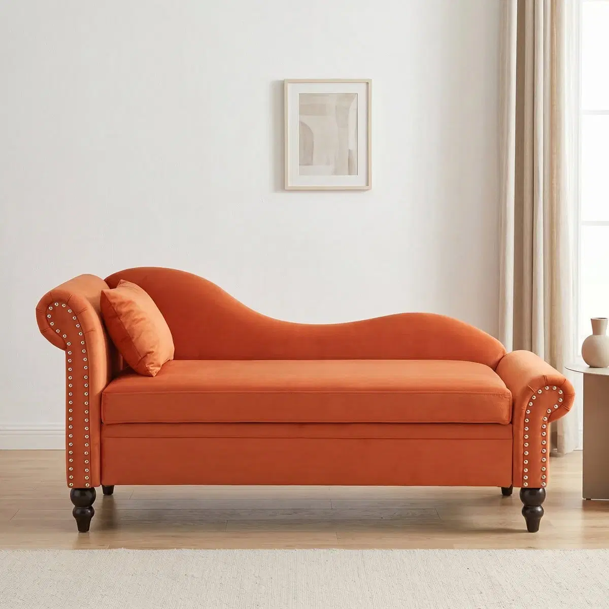 Front view of orange chaise storage bench with curved back, rolled arms, pillow and dark turned legs