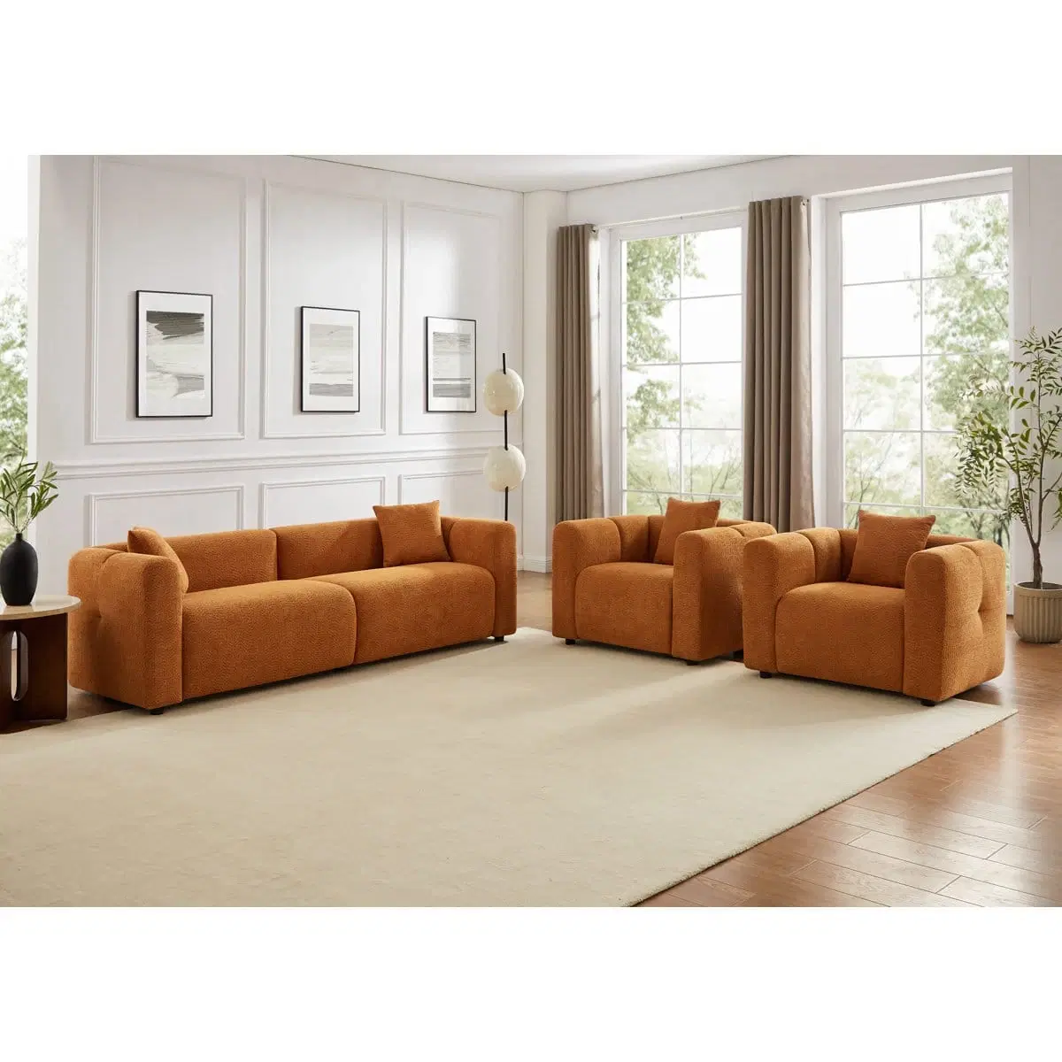 Front angled view of rust orange boucle 3-seater sofa styled in a bright living room with matching armchairs