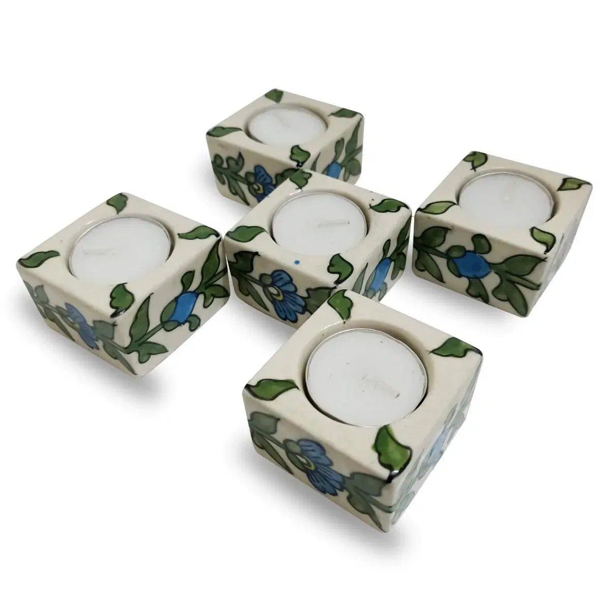 Angled group view of four matching floral tea light holders with candles inserted