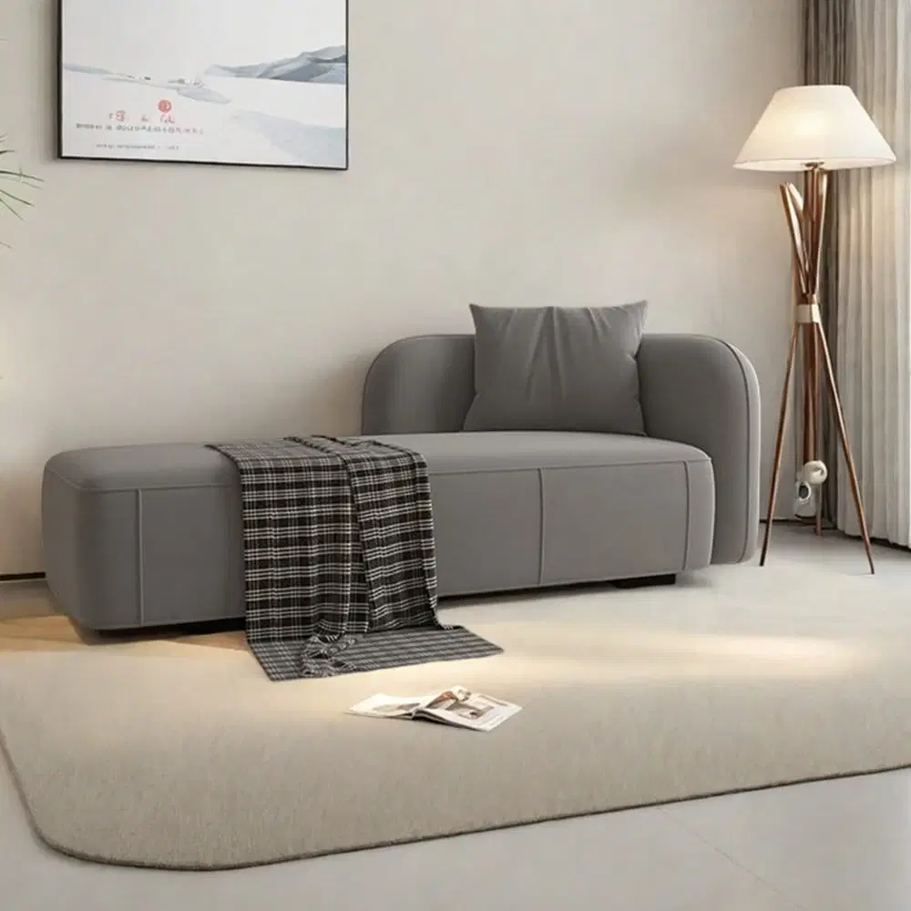 Grey upholstered chaise lounge sofa styled in a living room with a plaid throw and matching back cushion