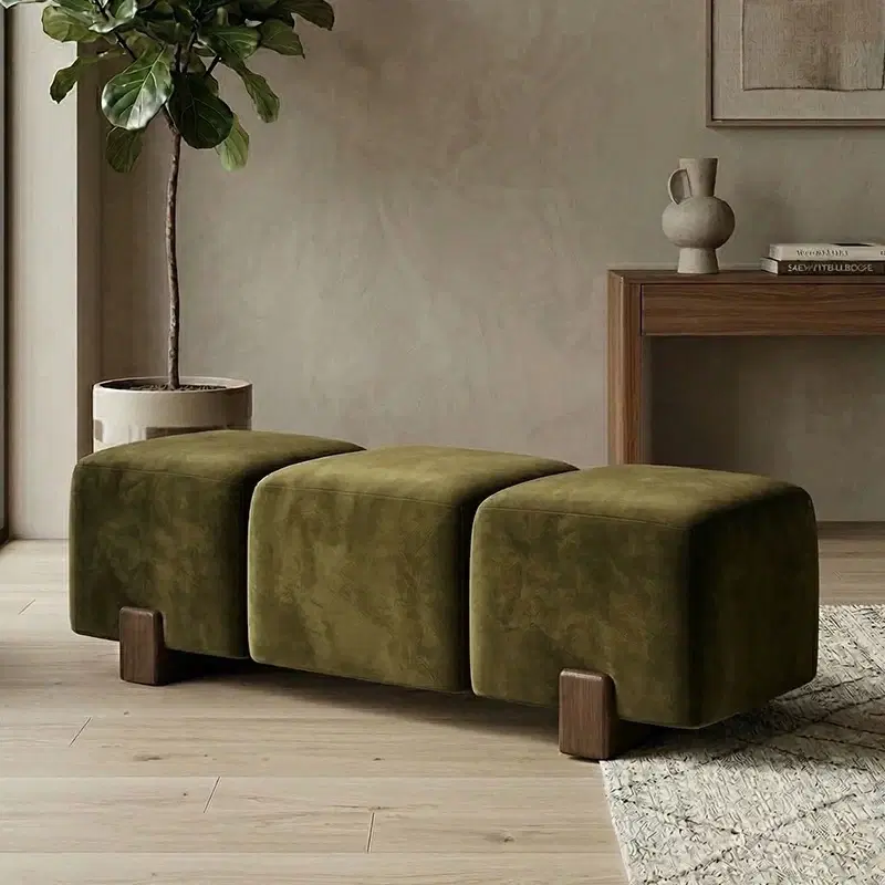 Olive green curved bench ottoman with three padded sections and short wooden legs in a styled living room