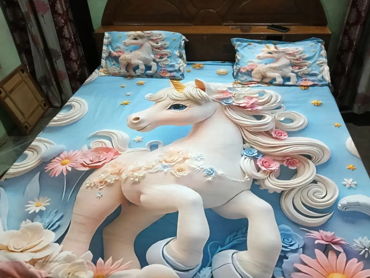 Blue bedsheet spread on a bed with large white unicorn print and two matching unicorn pillow covers