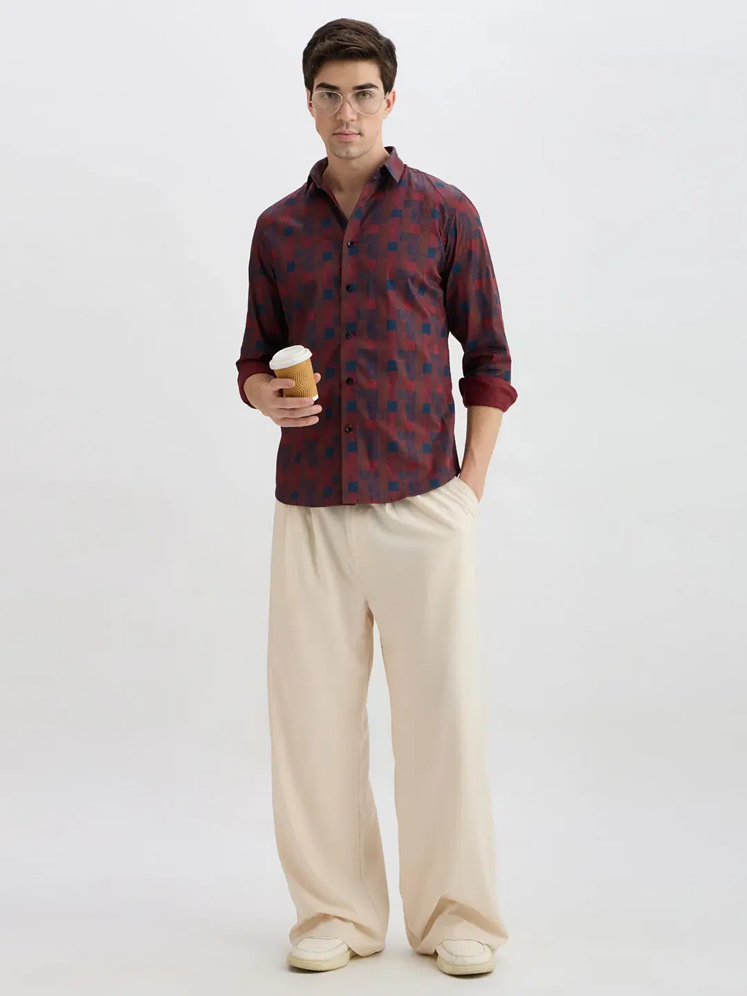 Full-length front view of maroon geometric print shirt styled with cream trousers and rolled sleeves