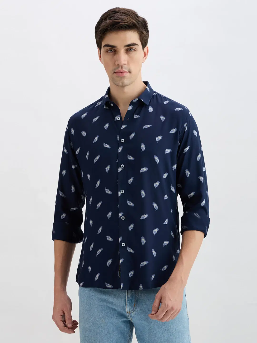 Front view of navy shirt with white feather print, worn with sleeves rolled up