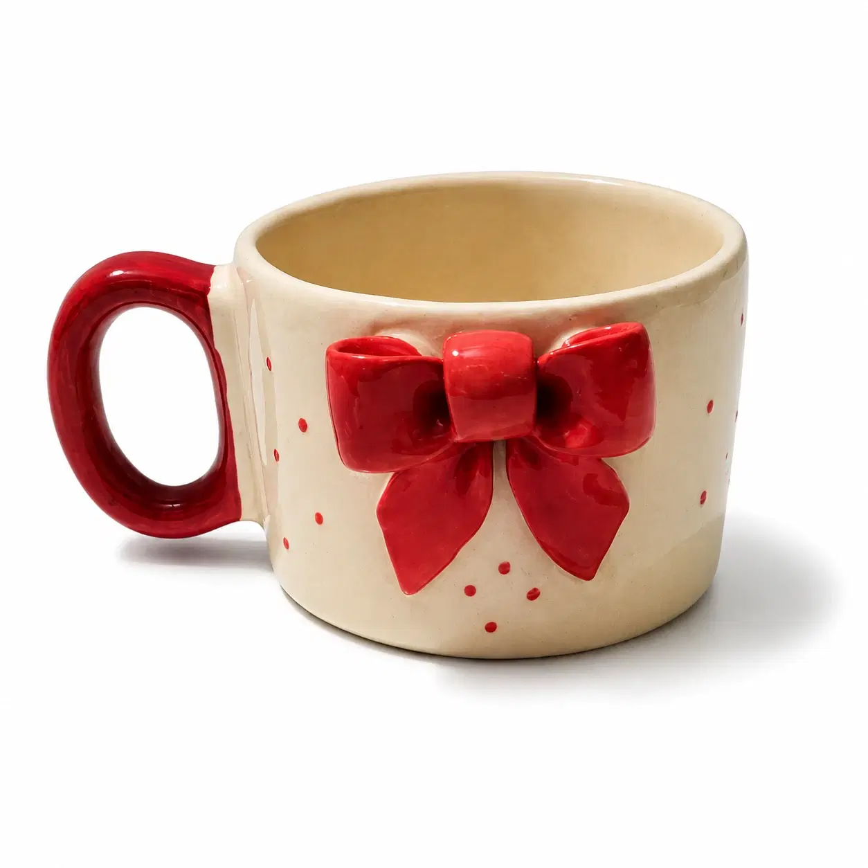 Cream ceramic mug with red handle and raised red bow detail on the front, shown at an angled front view