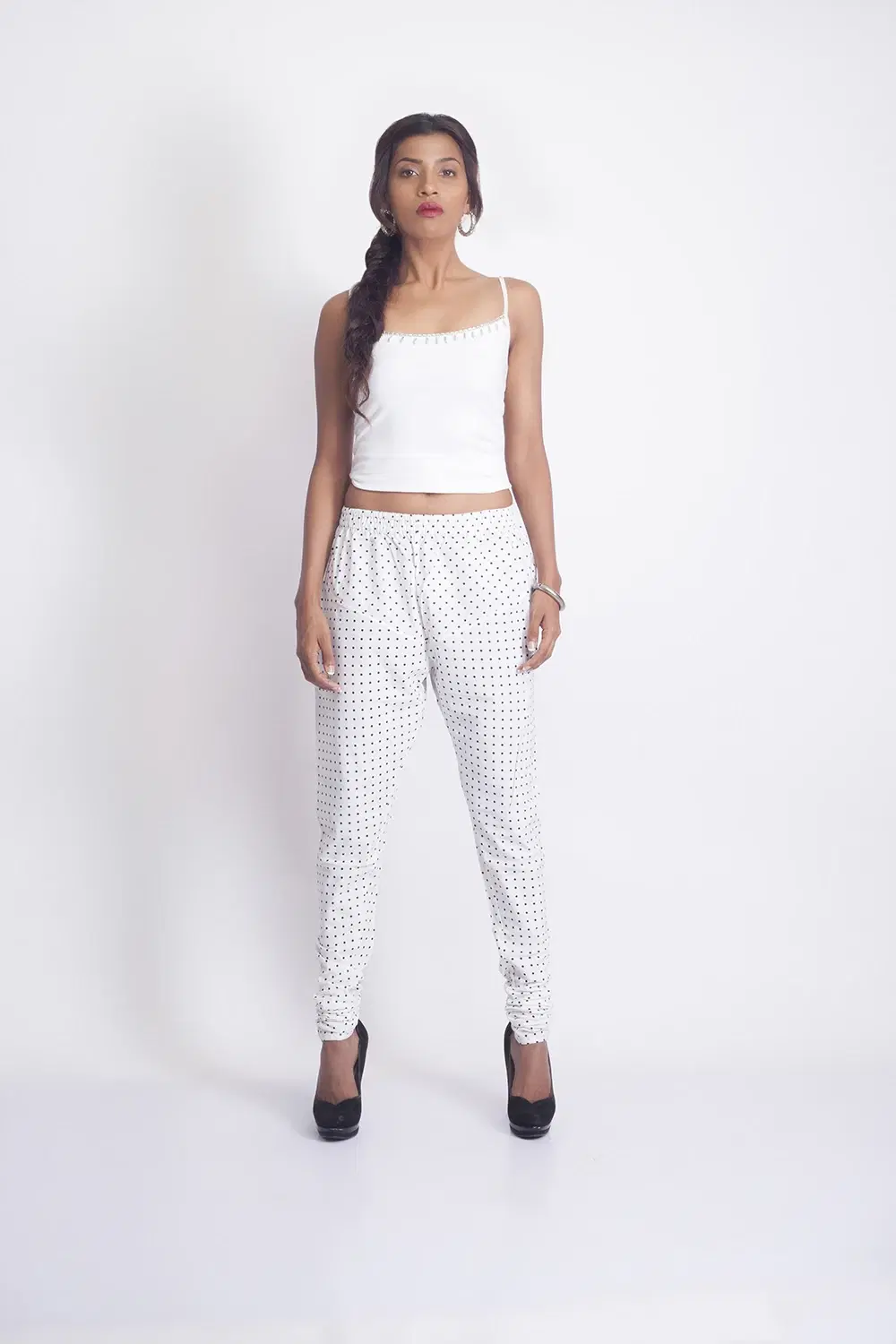 Front full-length view of white tapered slim fit pants with black polka dots and an elastic waistband