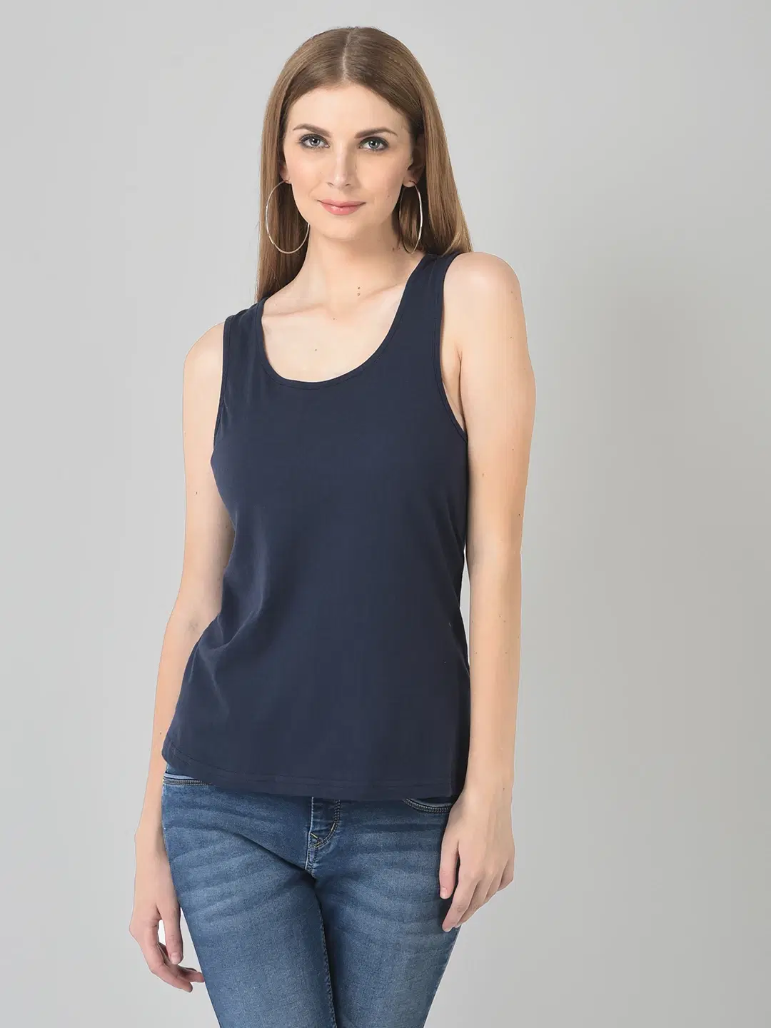 Front view of navy blue sleeveless tank top with scoop neck worn with blue jeans