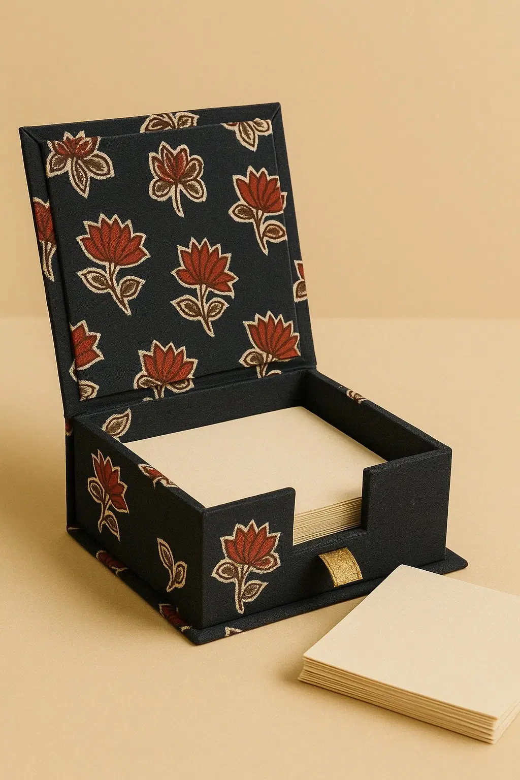 Open navy fabric memo box with rust floral print, square note pad inside and extra sheets beside it