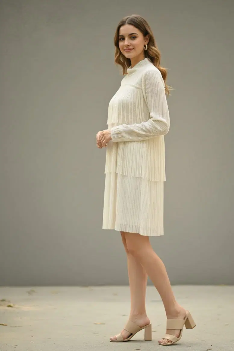 Woman wearing an ivory pleated knee-length long-sleeve dress with beige block-heel sandals
