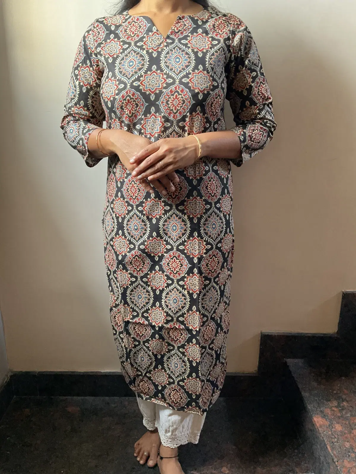Woman wearing a grey printed straight kurta with 3/4 sleeves and white lace-trim pants