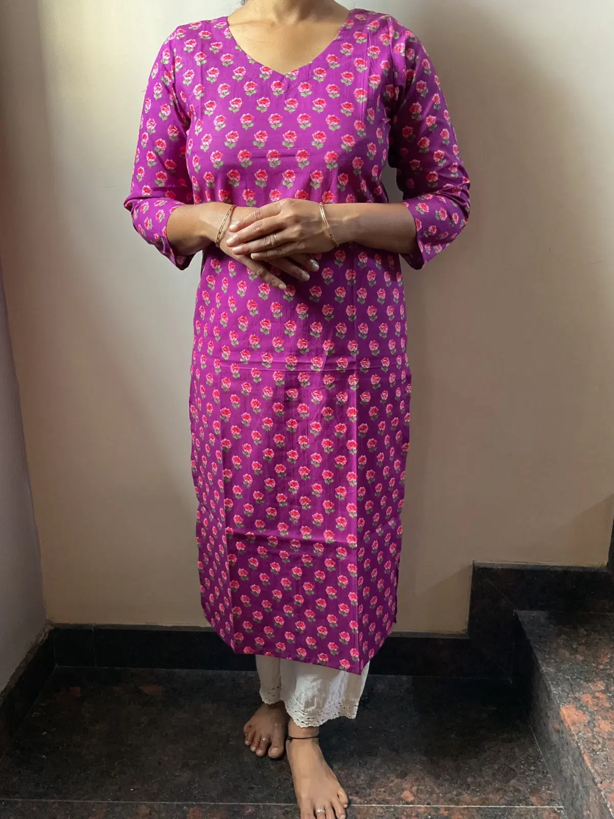 Woman wearing a purple floral printed straight kurta with 3/4 sleeves and white lace hem pants