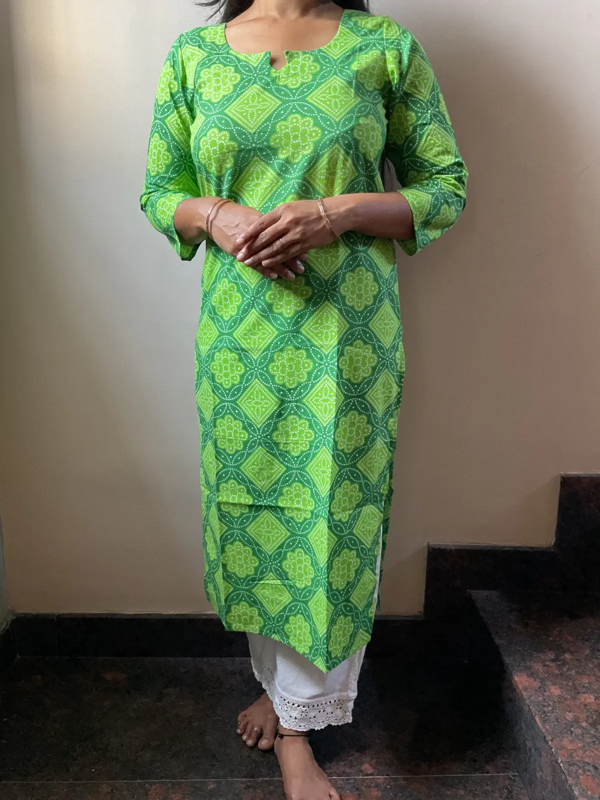 Woman wearing a green printed straight kurta with three-quarter sleeves and white lace hem pants