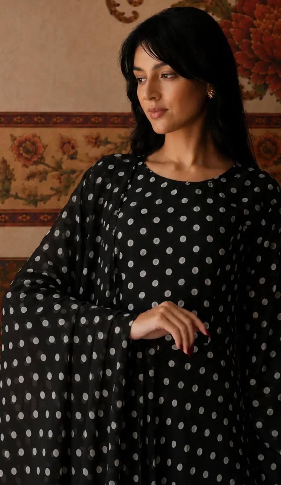 Woman wearing a black polka dot tunic top with flowing bell sleeves