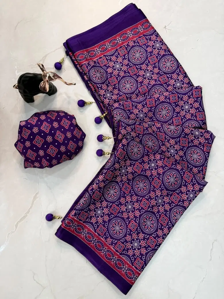 Purple printed ethnic dress material with tassel dupatta and matching fabric accessory on a light background