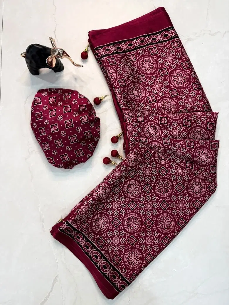 Maroon printed saree with geometric motifs, border detailing, tassels, and matching blouse piece