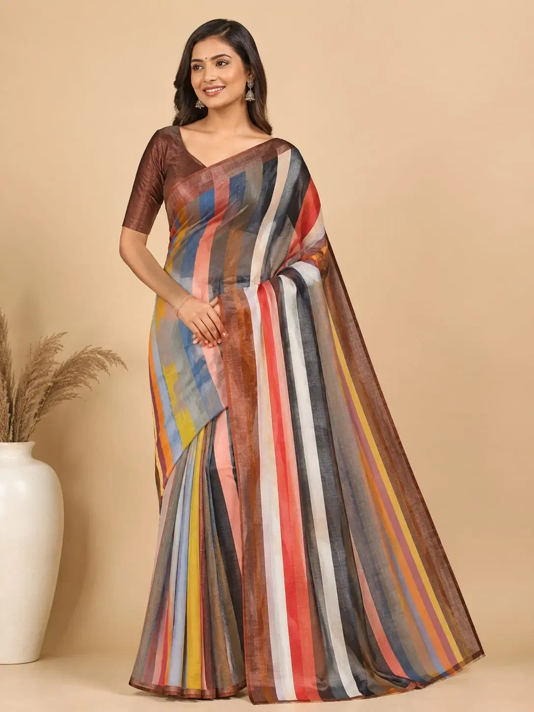 Woman wearing a multicolor striped saree with a brown blouse against a beige background